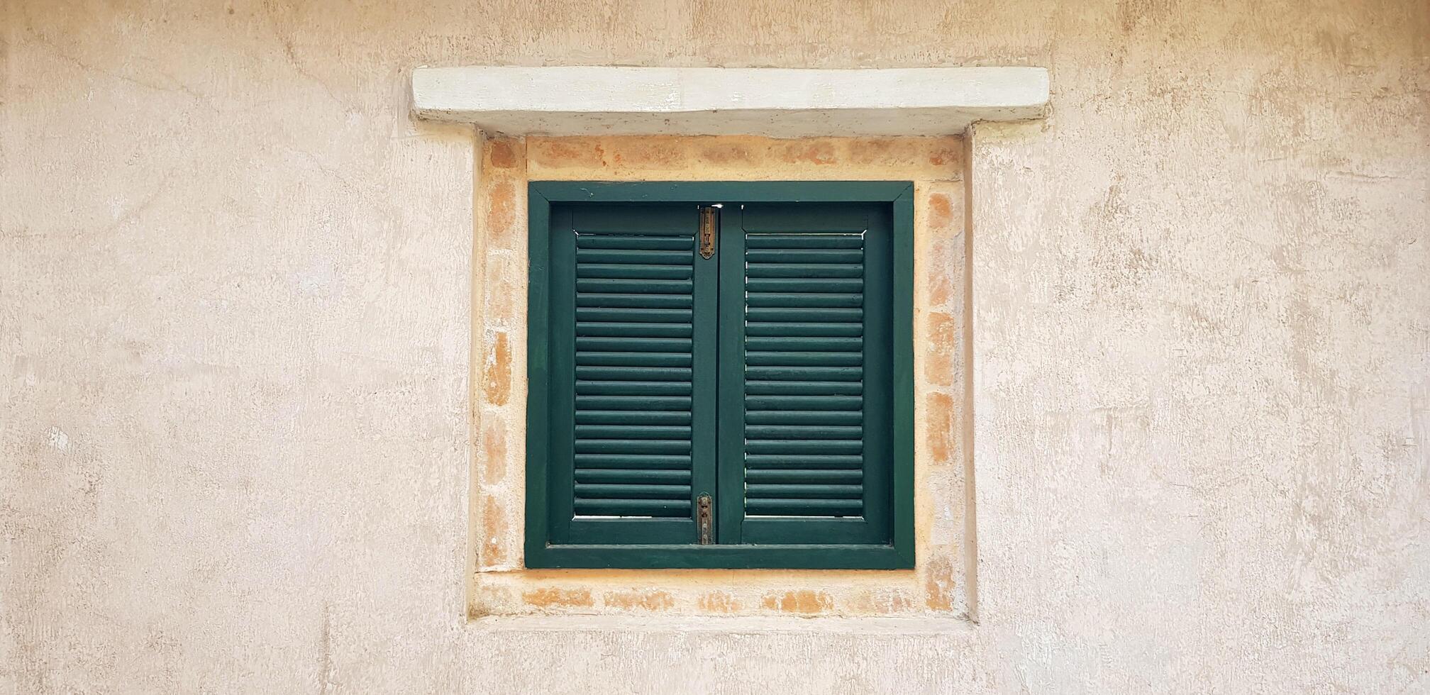 Green vintage wooden window closed on rough wall at urban. Design, Decoration and Beauty of object. photo