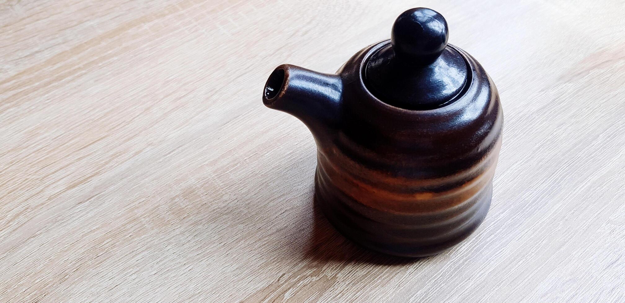 Black ceramic jug or mug tea putting on the wooden table with copy space. Sigle object, Dishware in Japan style,, Design and Container concept. photo