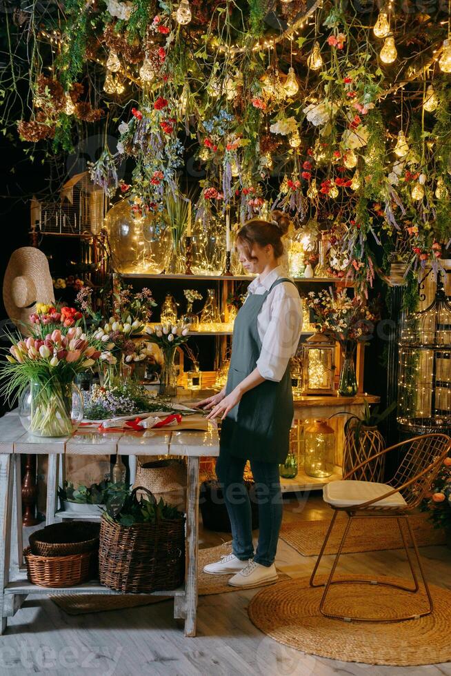 A woman in her florist shop collects bouquets of flowers. The concept of a small business. Bouquets of tulips for the holiday on March 8. photo