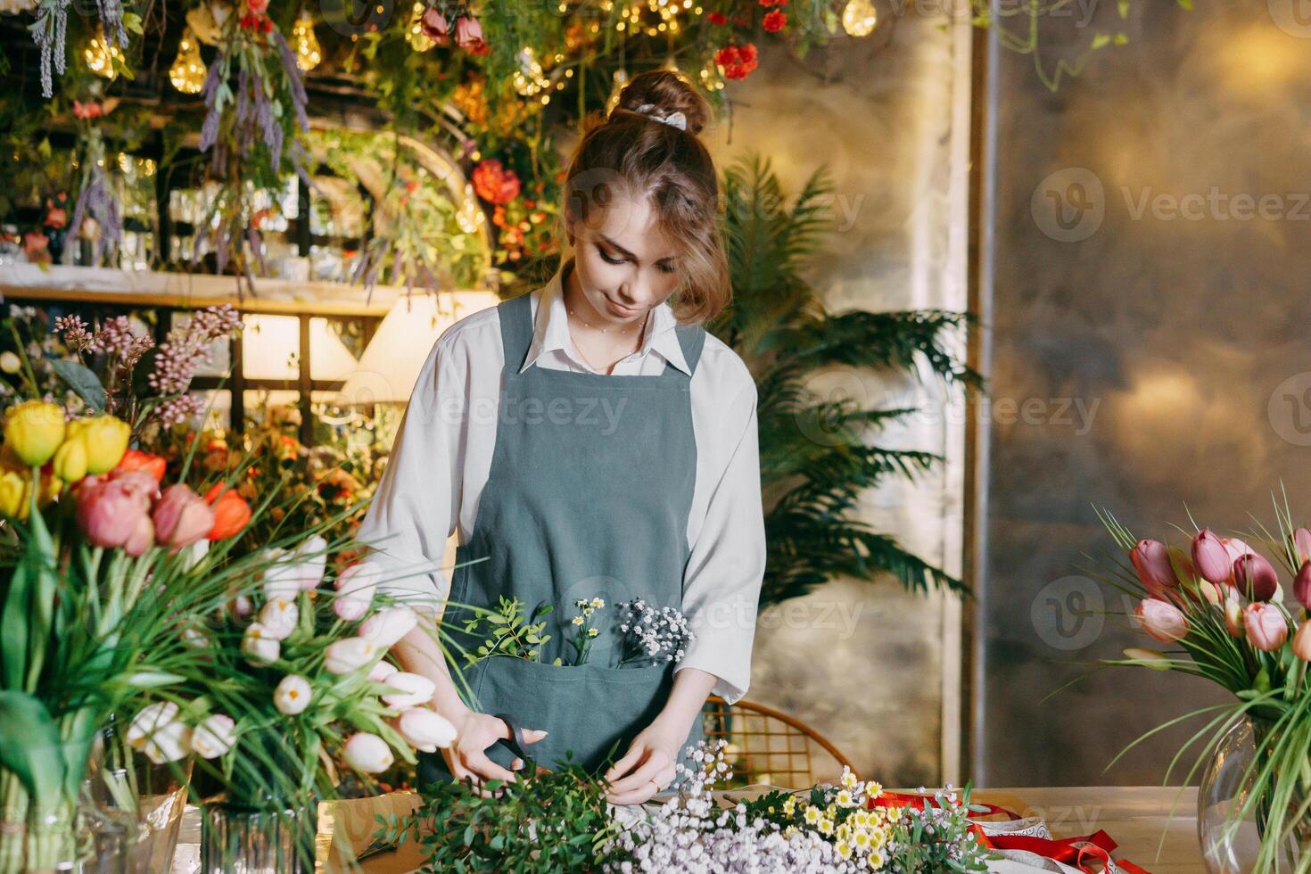 A woman in her florist shop collects bouquets of flowers. The concept of a small business. Bouquets of tulips for the holiday on March 8. photo
