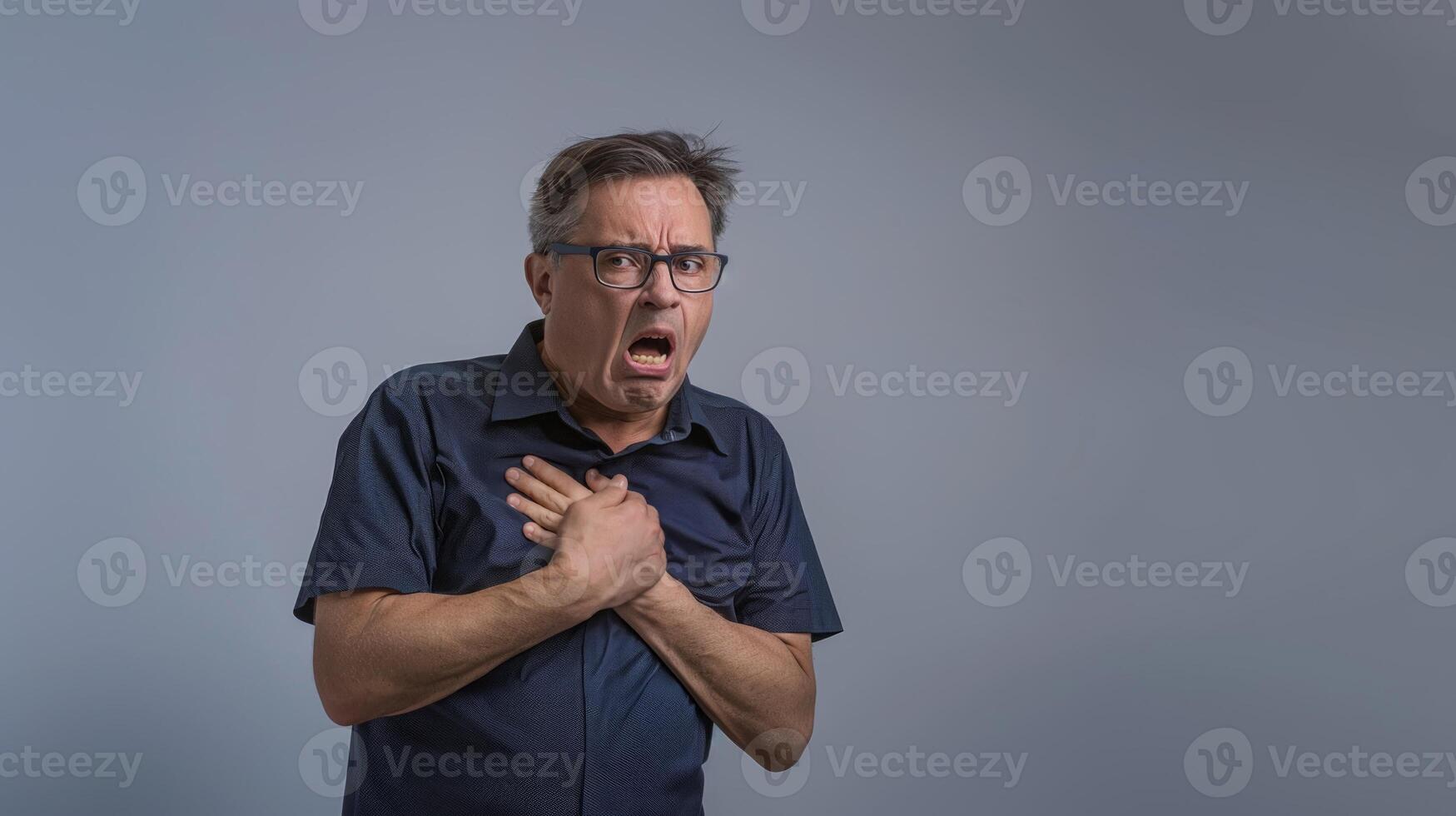 A middle aged Indian man holding his hand to his chest while having bad breath in an isolated on a grey background photo
