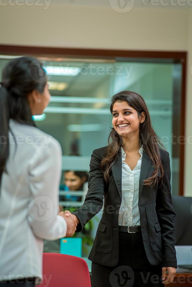 A happy young Indian woman rejoicing and shaking hands with an employee when was recruited during an interview in the office photo