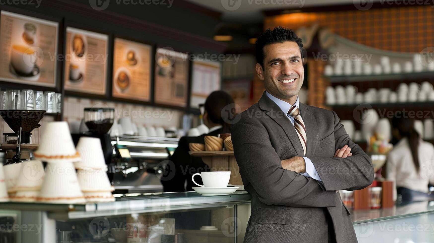 A confident Indian businessman stands at a coffee shop smiling and looking at the camera photo