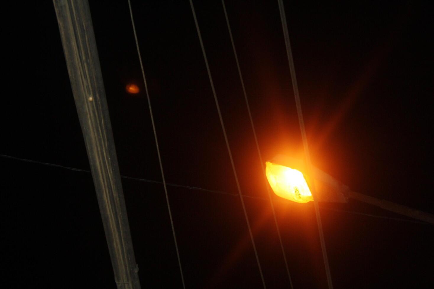 Streetlight glowing at night with power lines photo