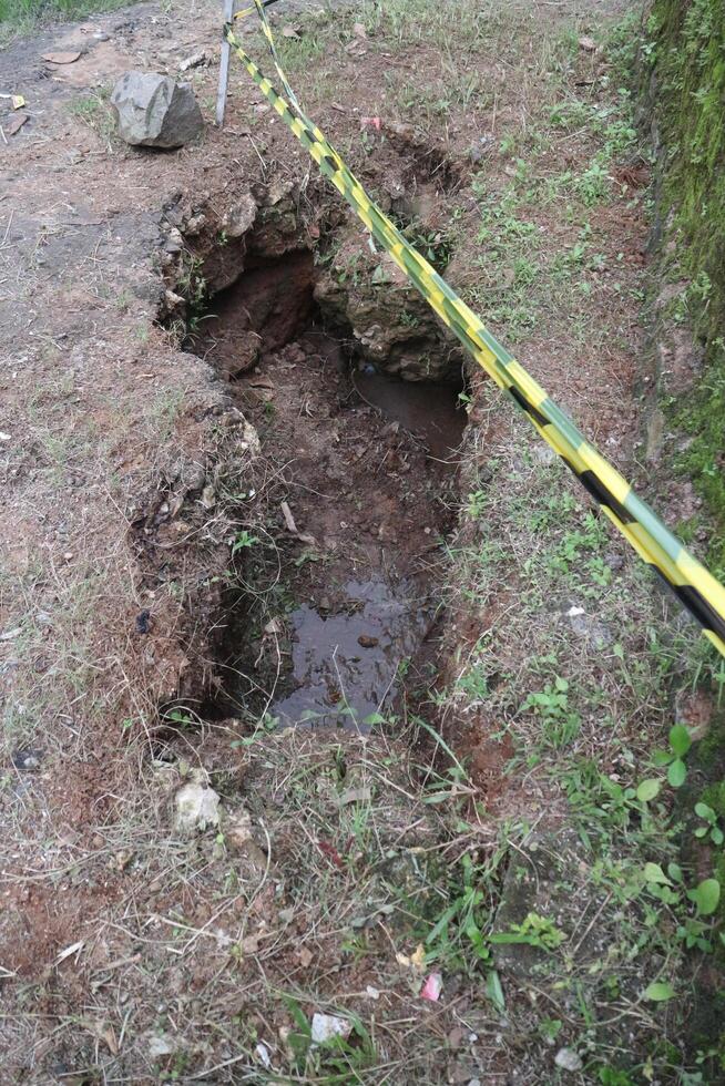 Large hole in the ground with caution tape photo