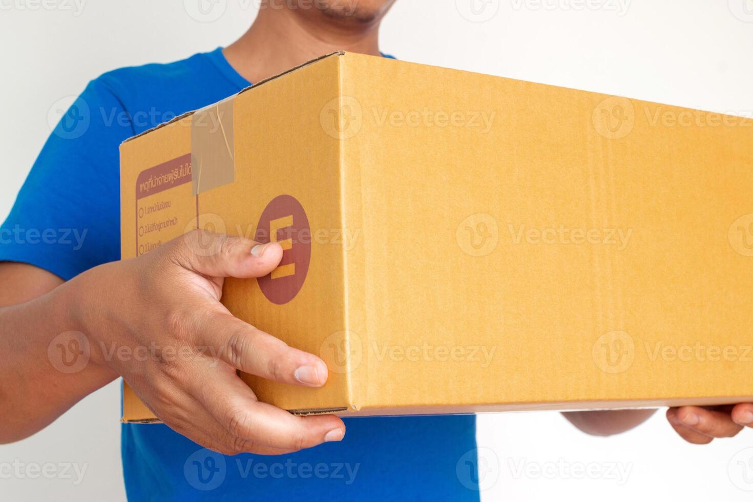 Closeup hands of delivery man holding package to deliver. Courier hand holding brown box isolated on white background. photo