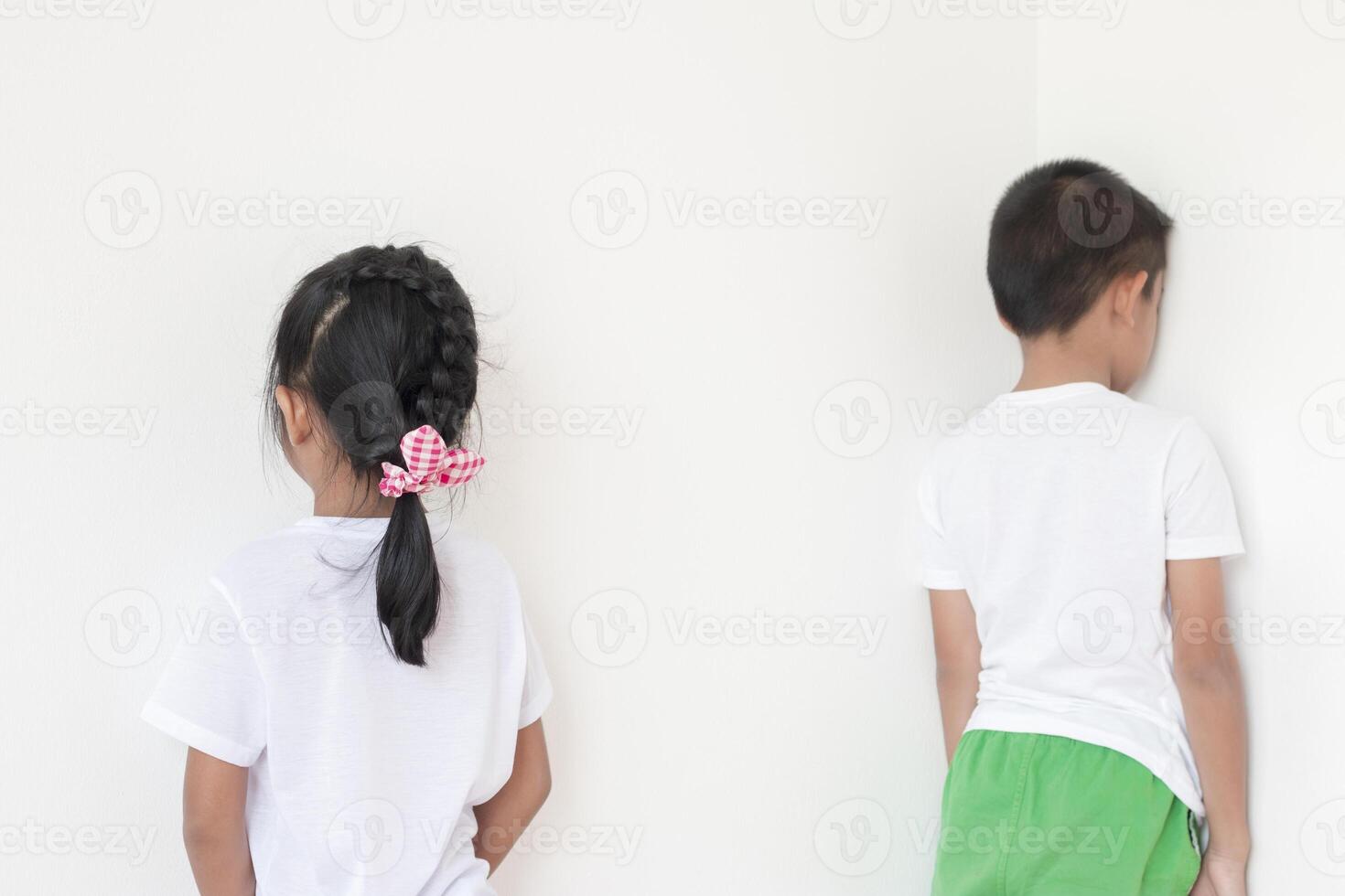 Boys and girls standing in front of the wall in the corner of the room Because of being punished by parents. photo