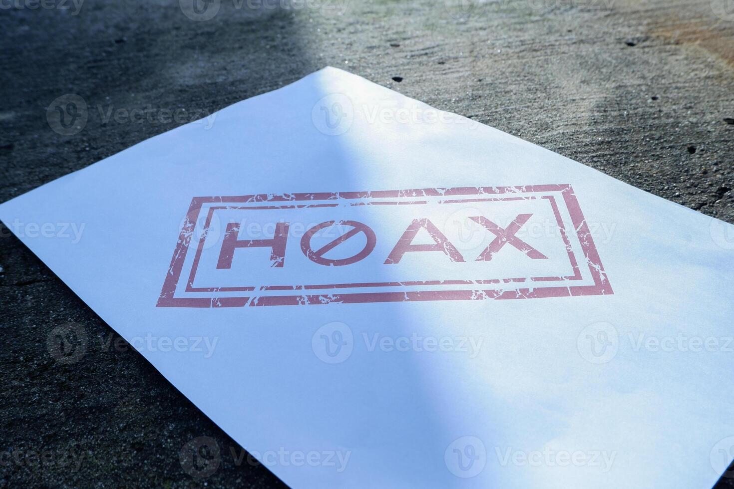 a piece of white paper on the floor with hoax written on it. illustration concept of stop giving false or fake news photo