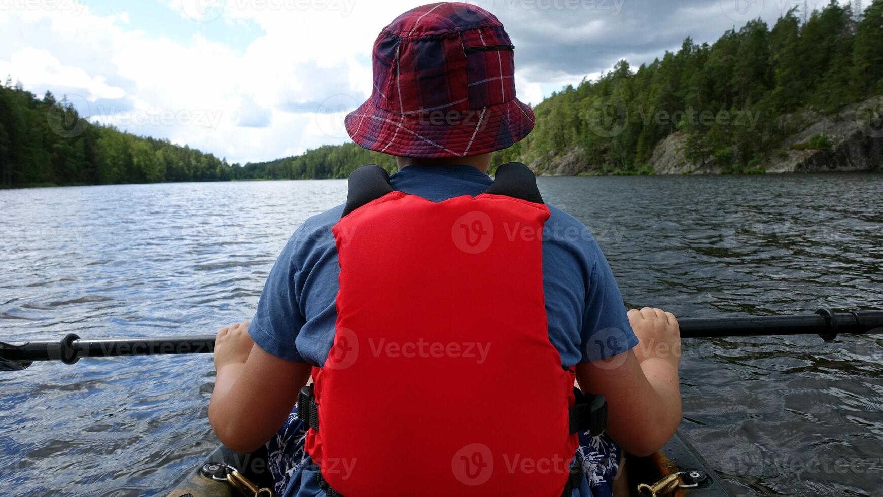 A man from behind, rests with his paddle in a canoe on the water photo