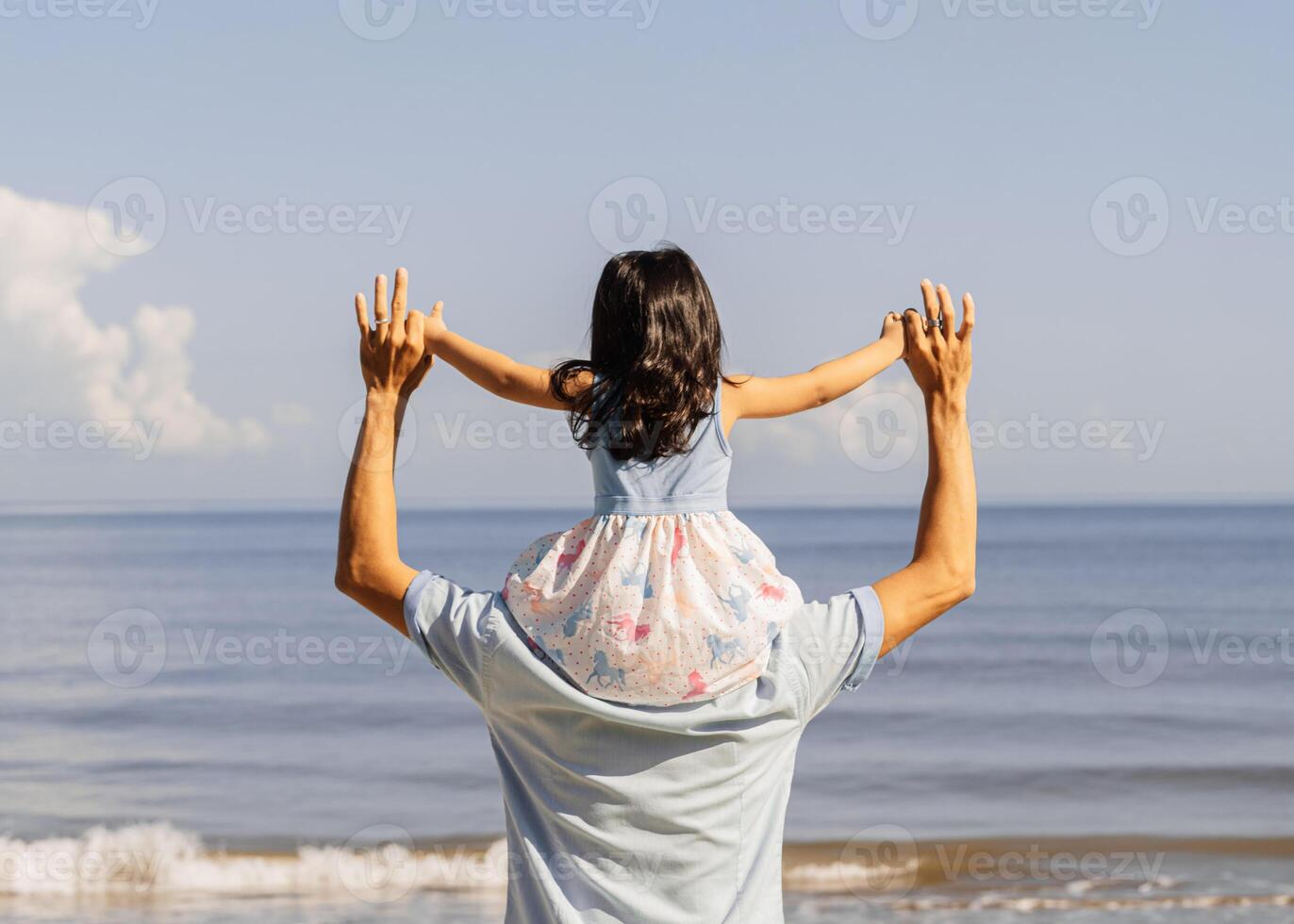 Fun father holding a his daugther over head walking to a beach. photo