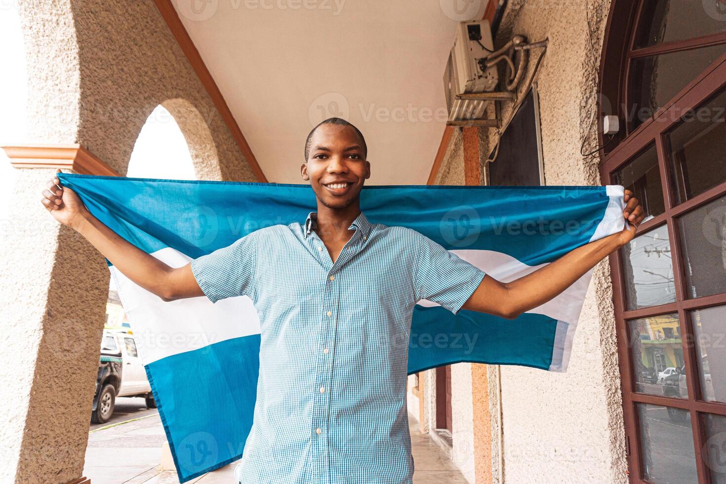 Wide angle portrait of a proud and smiling young man holding a flag of Honduras. photo