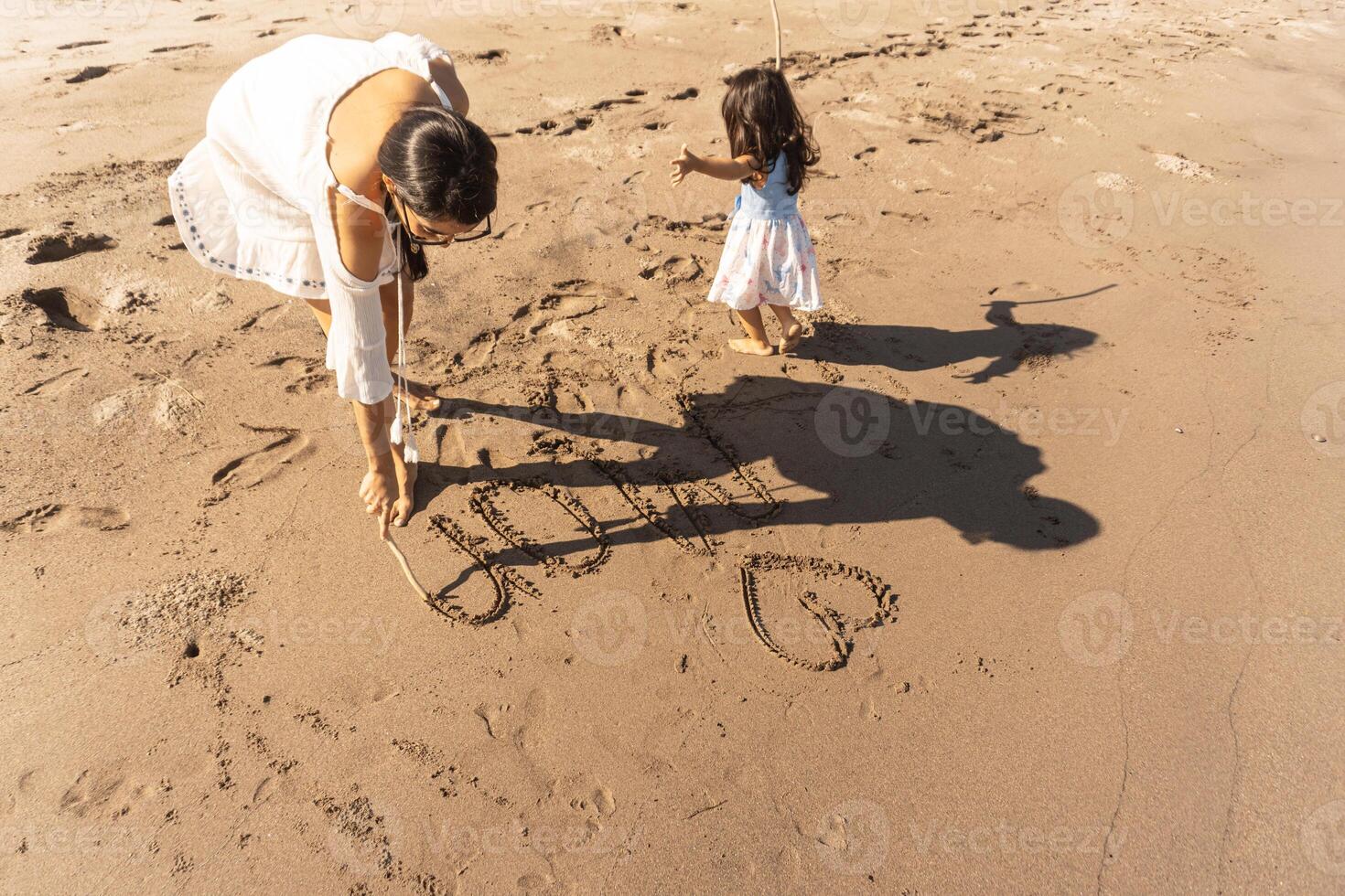 Mother and daughter playing together in the sand on the beach. photo