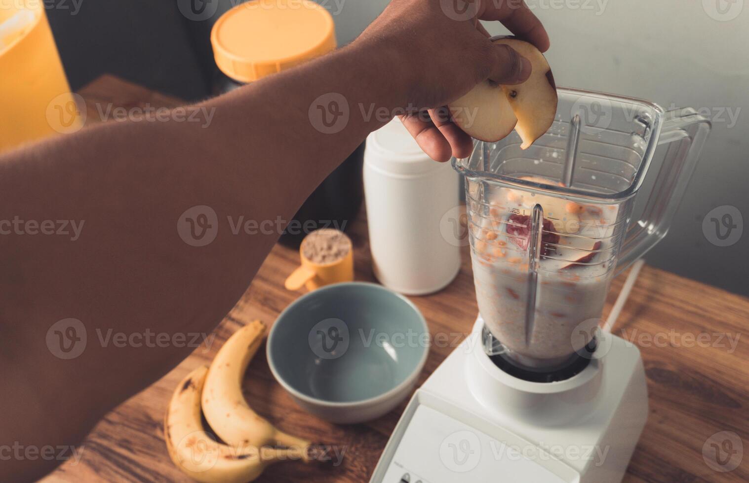 Hand holding an apples, preparation of smoothie with milk, banana and oatmeal. photo