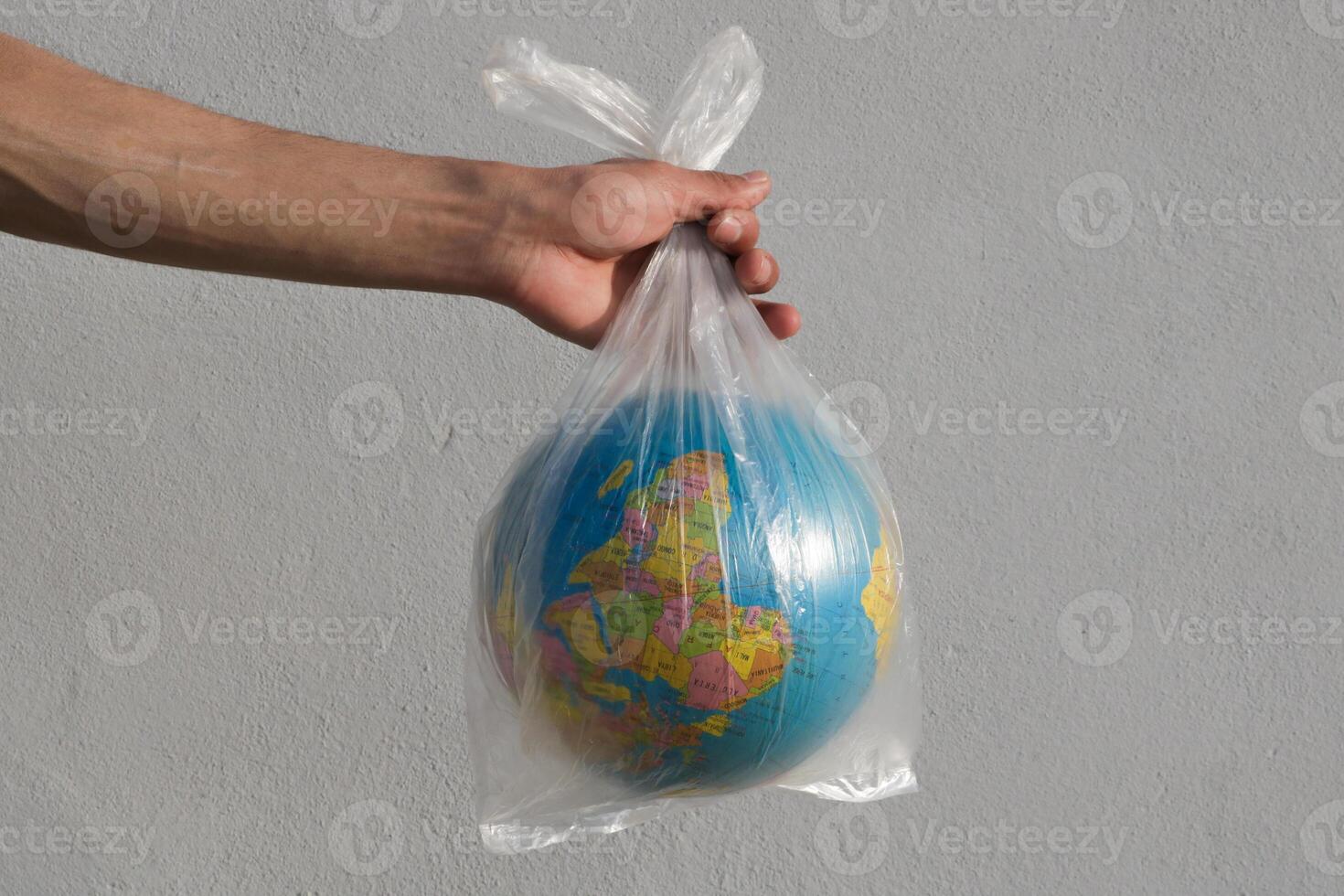 Globe in a plastic bag. Concept of plastic pollution of the earth on white background. photo