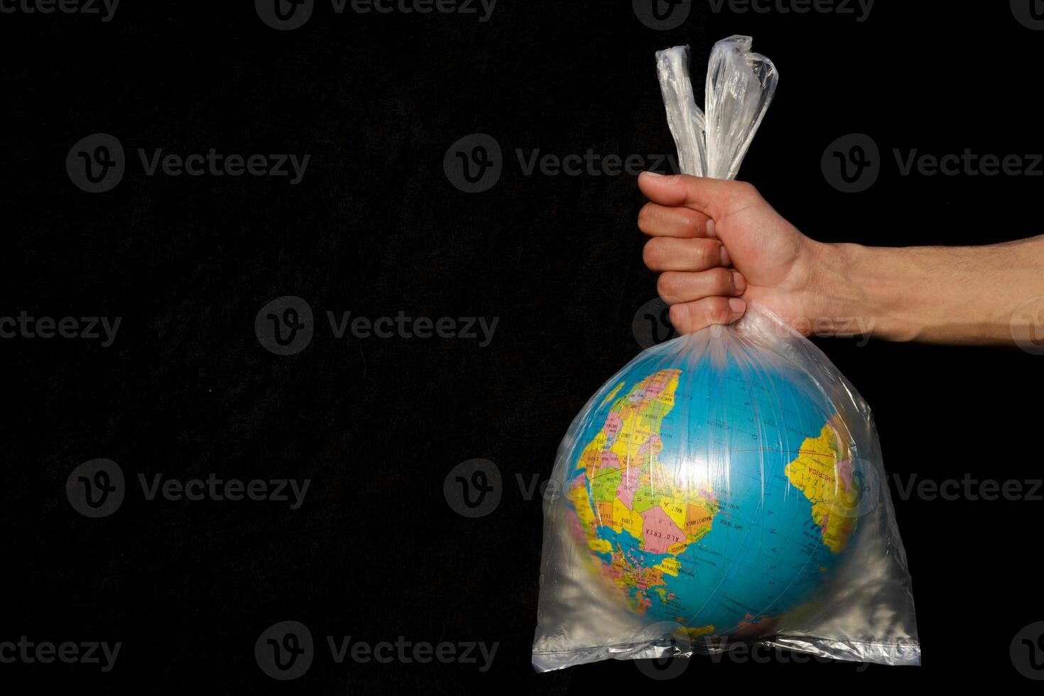 Earth wrapped up in plastic bag. Globe in a plastic bag. Concept of plastic pollution of the earth. World Environment Day concept. Copy space. Save Earth Concept on black background Selective focus. photo