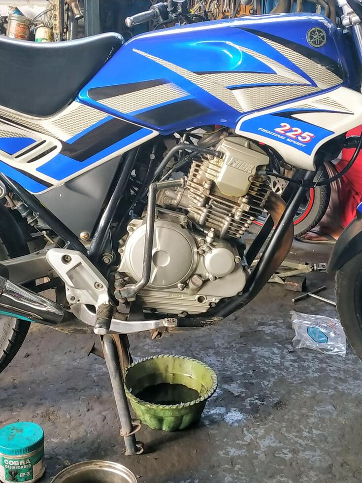Banyumas, Indonesia, 2024 - Change motorbike oil at a roadside repair shop photo
