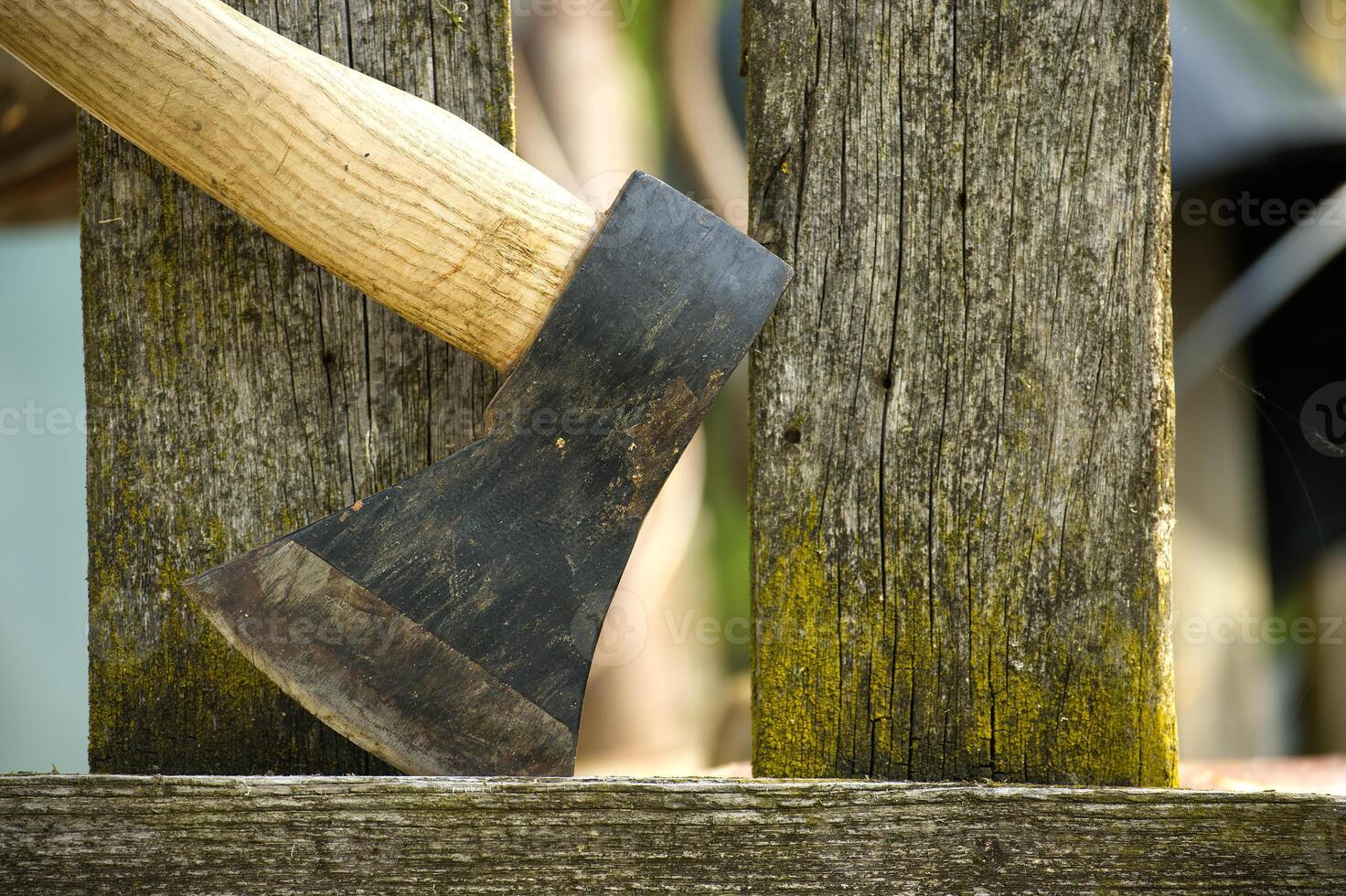 Detailed depiction of an axe embedded in an aged, weather wooden fence photo