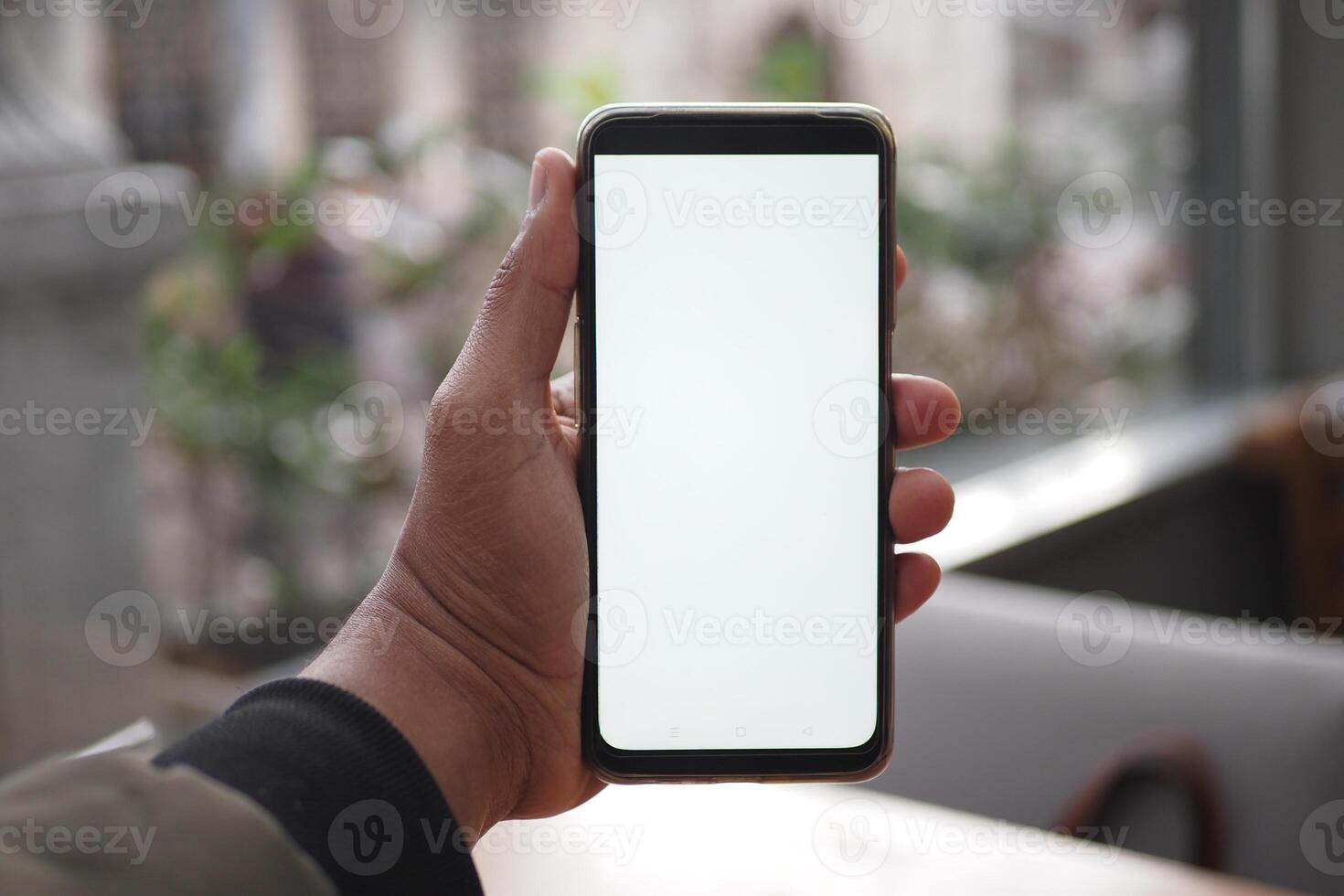 A hand holds a smartphone with a blank screen, suitable for app or website mockups photo