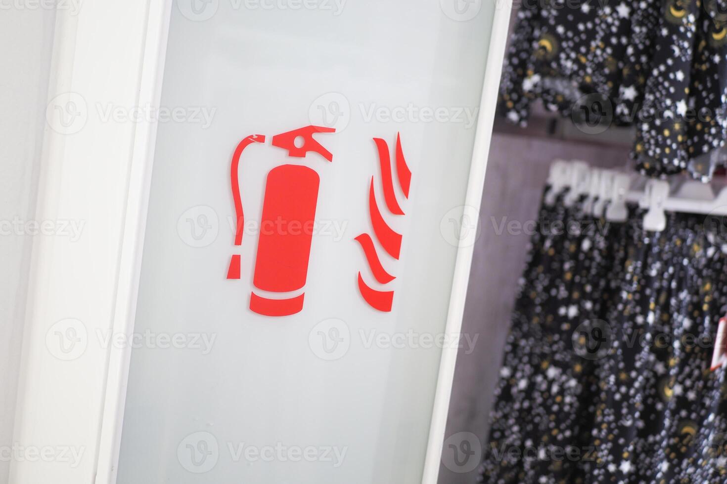 In a store, there is a fire extinguisher symbol displayed alongside clothing items photo