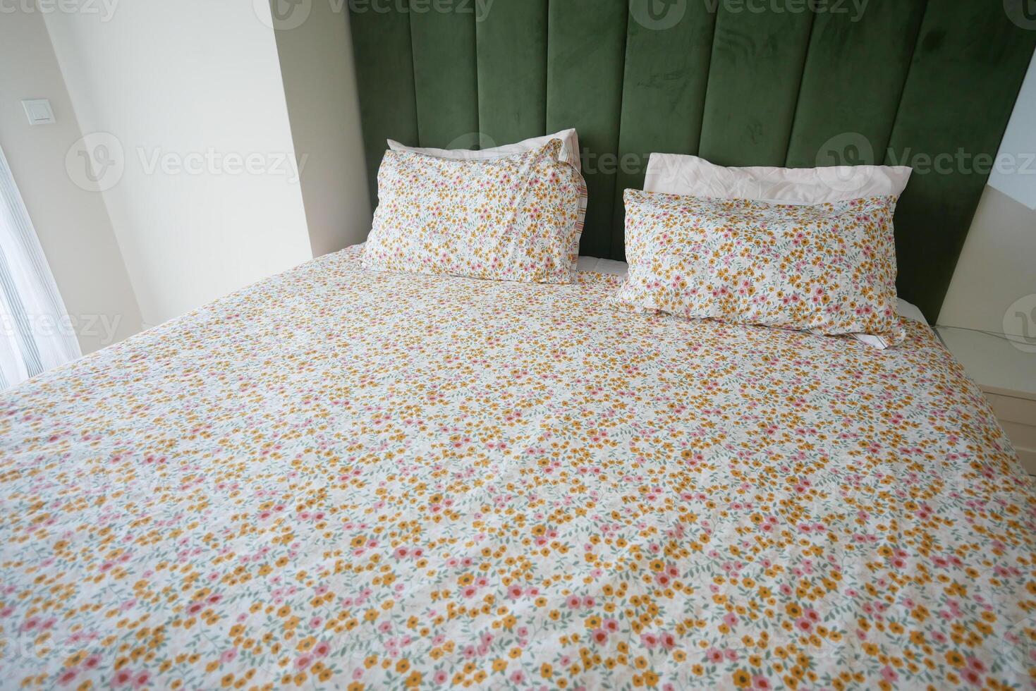 A bed with floral bedding in a bedroom with hardwood floors and cozy linens photo