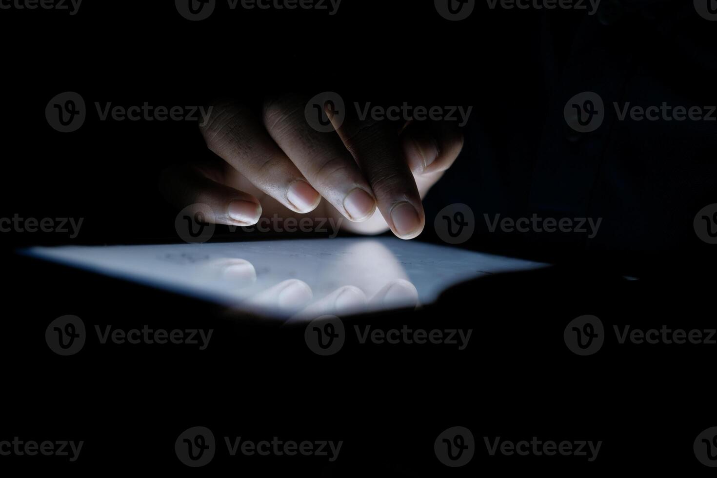 In a dark room, a glowing tablet is used, showing modern technology and connectivity photo