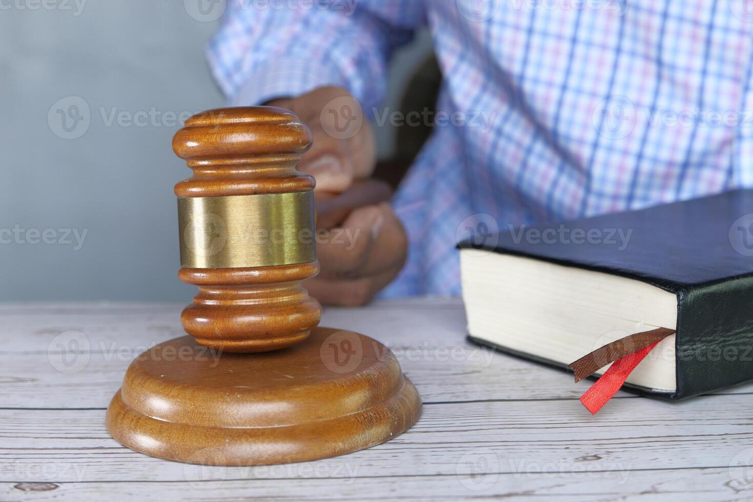 judge hand holding a gavel with book on table, close up photo
