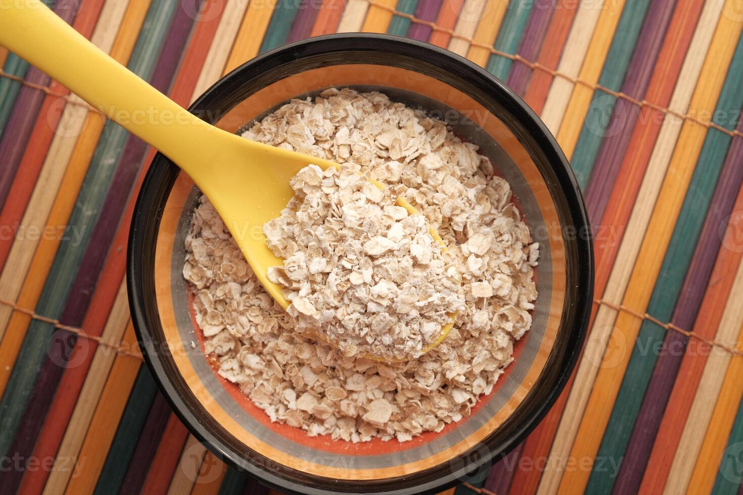 Rolled oats or oat flakes in a bowl on table photo