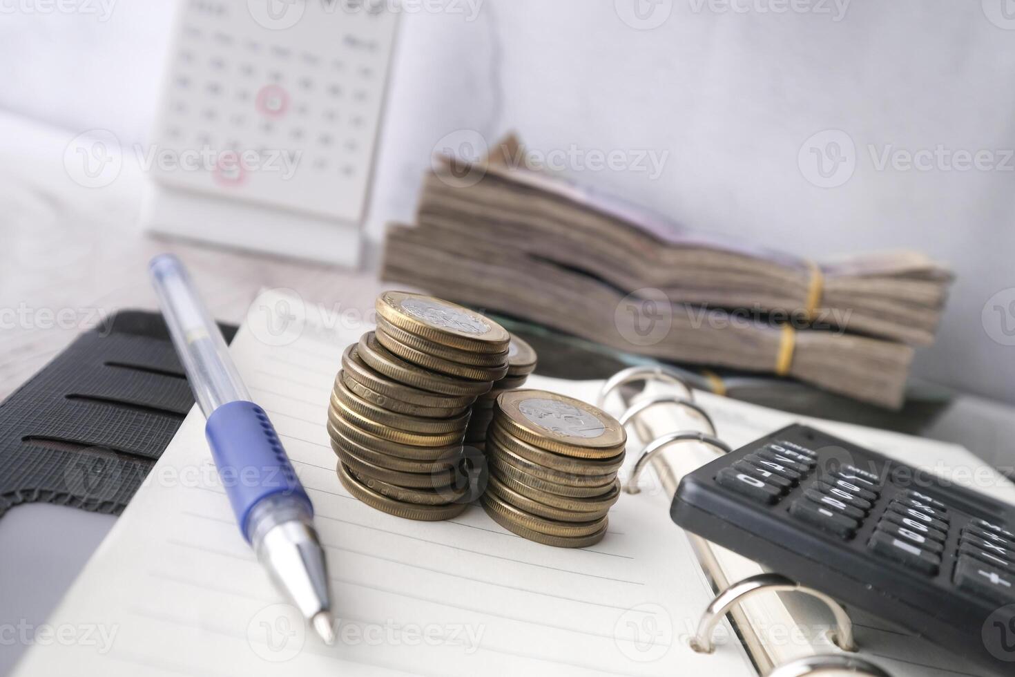 stack of coins, cash and calculator on notepad. photo
