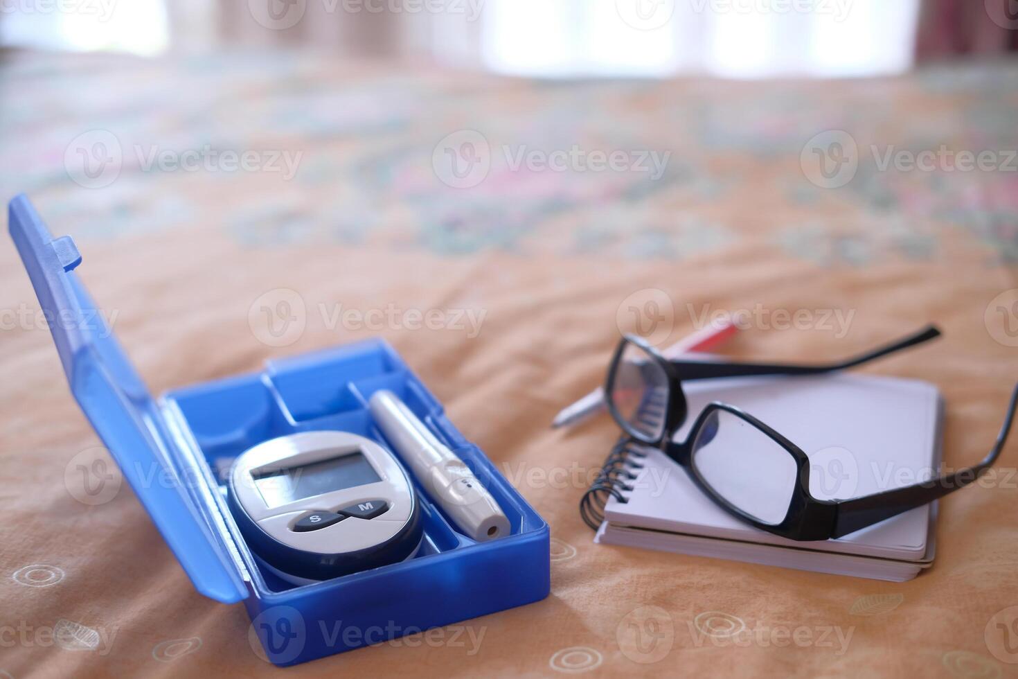 diabetic measurement tools and eyeglass on bed photo
