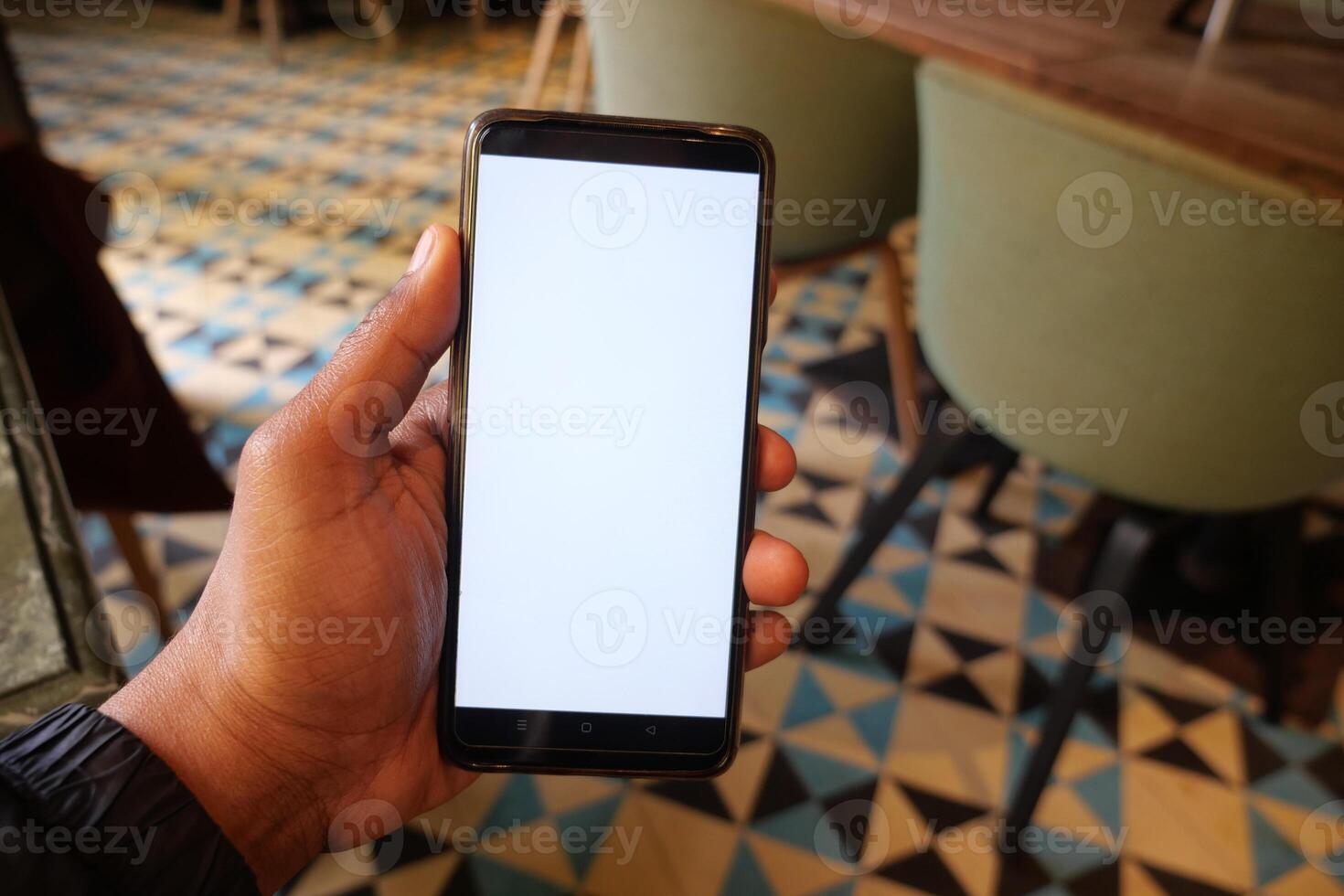 young man hand using smart phone with white screen at cafe photo