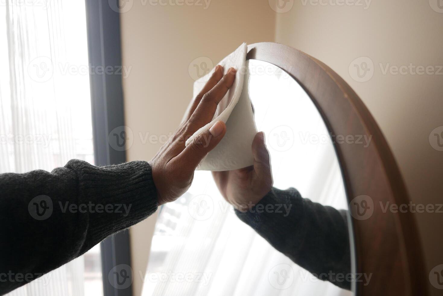 Man Cleaning a home Mirror with a tissue . photo