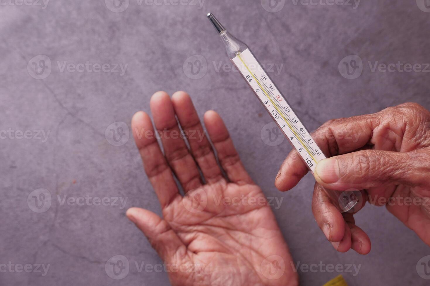 Sick senior woman hand holding thermometer . photo