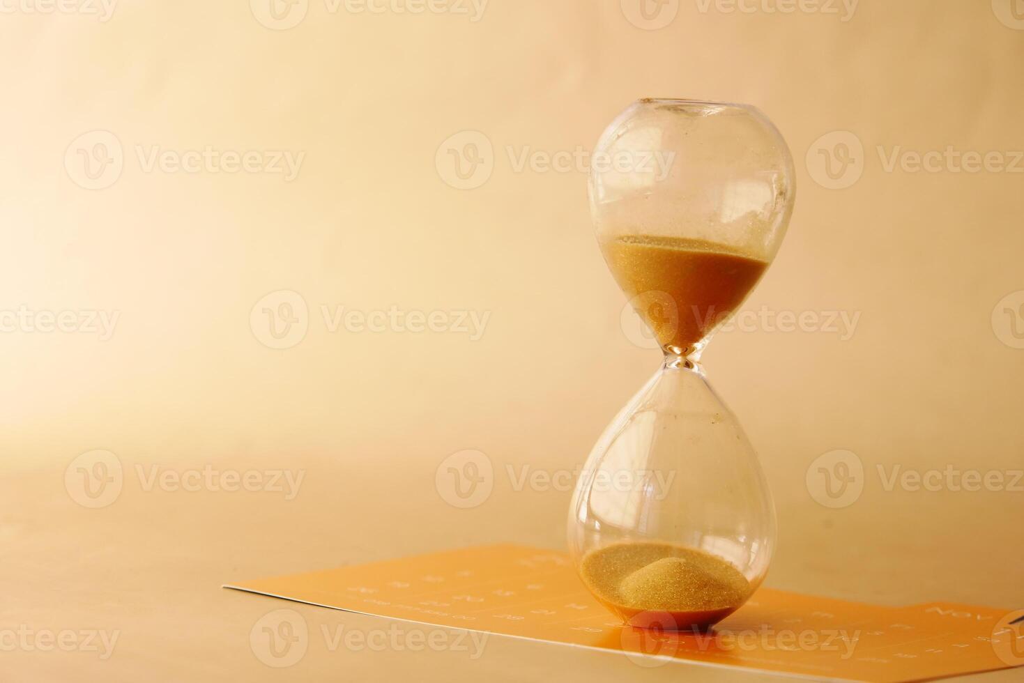 hourglass on table, sand flowing through the bulb of sandglass photo