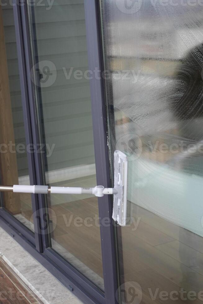 Rubber squeegee cleans a soaped window. photo