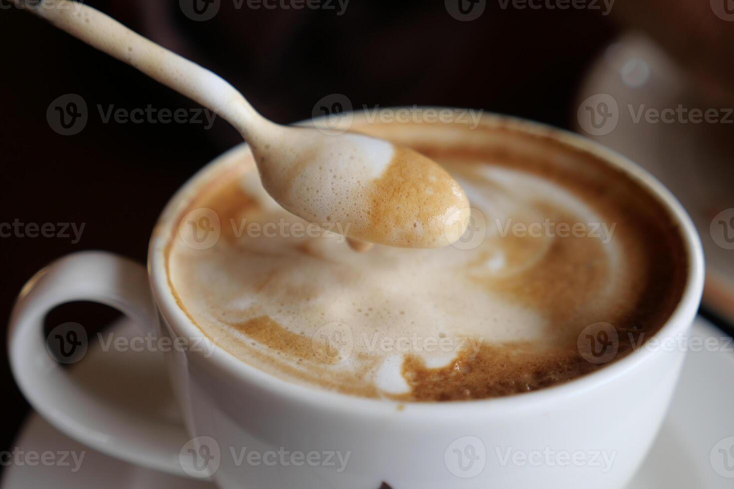 Enjoy a steaming hot cappuccino with swirling foam and a spoon for your delight photo