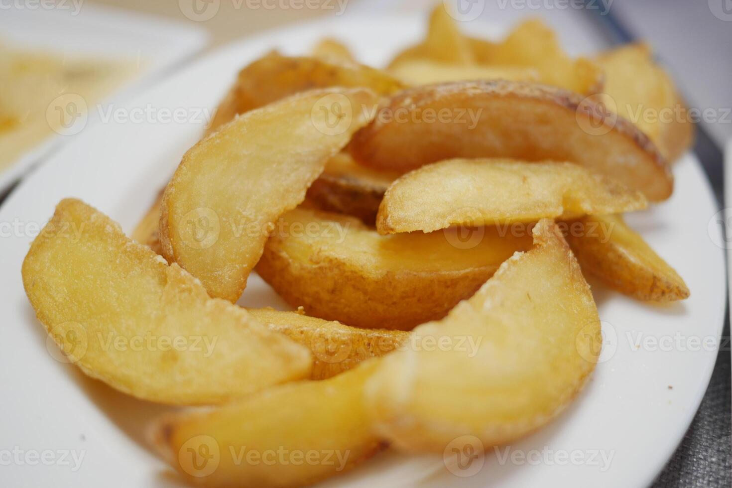 A mouthwatering closeup of delicious, crispy golden potato wedges served on a white plate photo