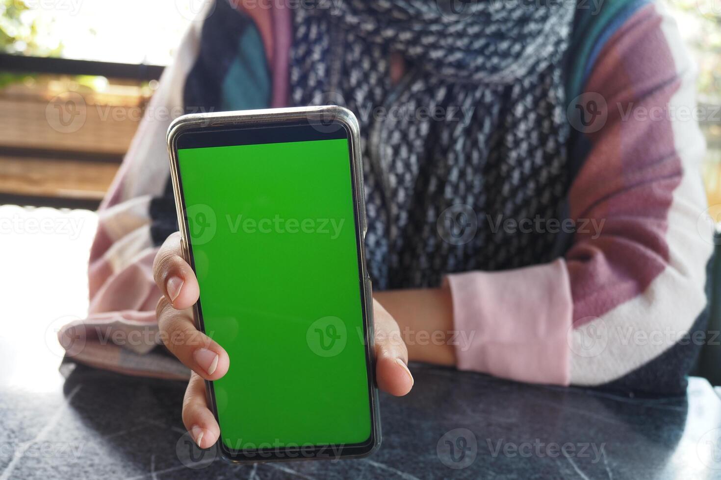 A person using smartphone with green screen, showcasing modern technology and digital interaction photo