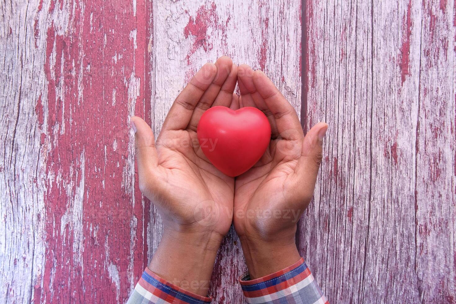 hombre participación rojo corazón en manos en de madera mesa . foto