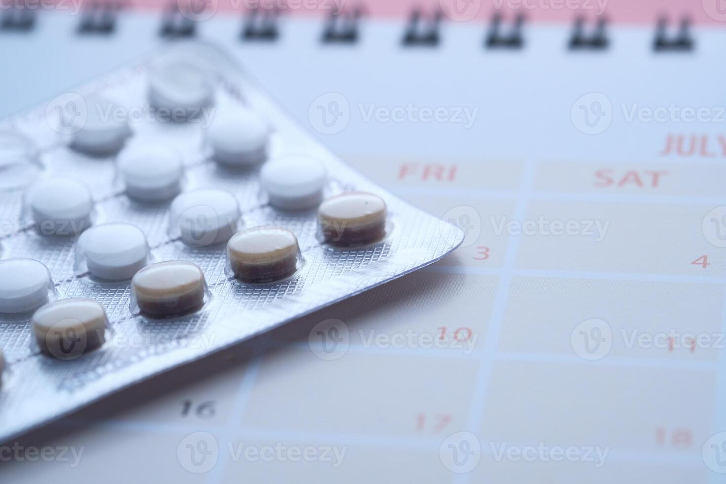 Close up of birth control pills and calendar on table photo