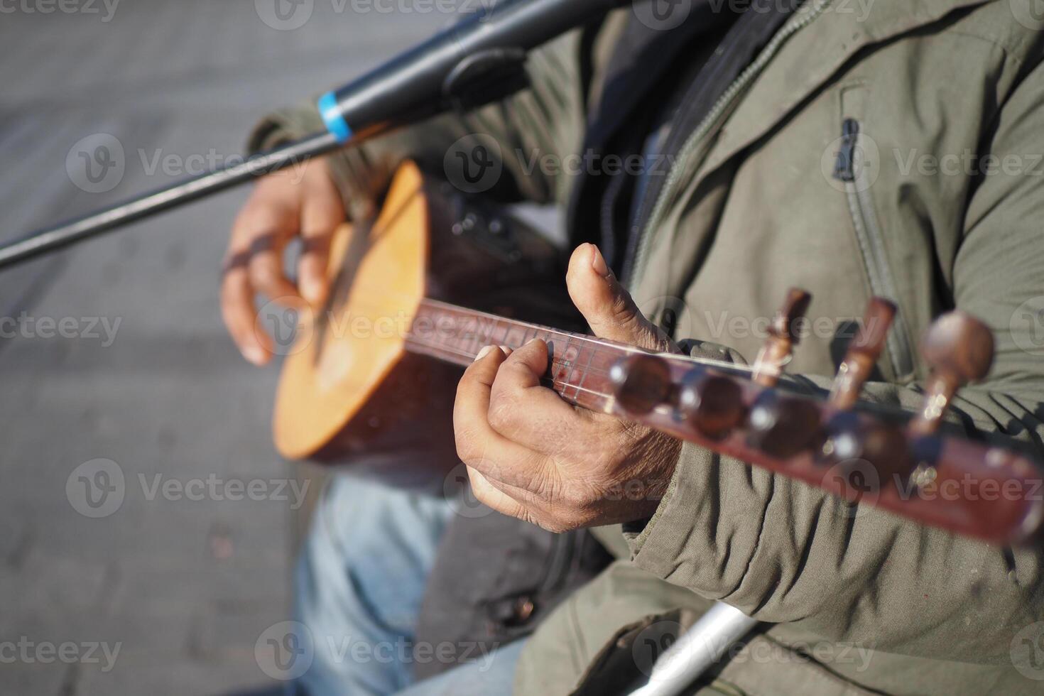 Street musician playing a string instrument in a traditional outdoor performance setting photo