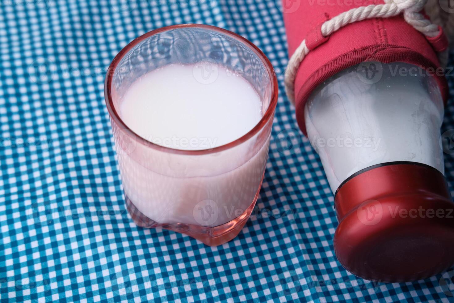 Close up of glass of milk and jar on table photo