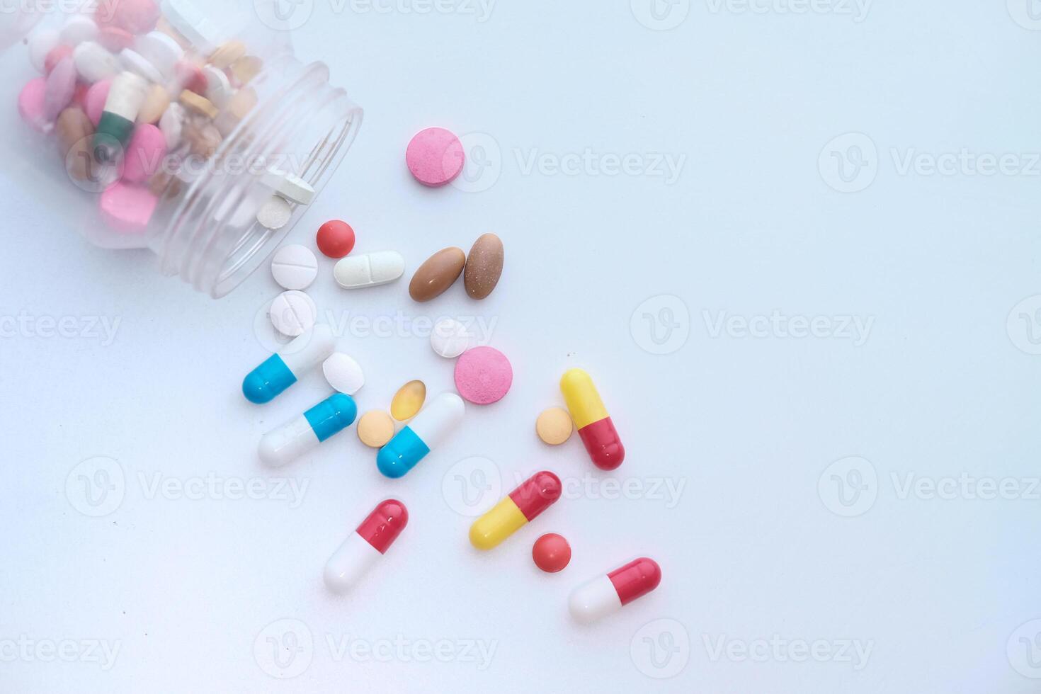 pills spilling from a container on white background photo