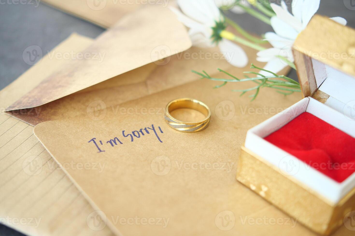 Note with the sorry word next to a wedding ring. photo