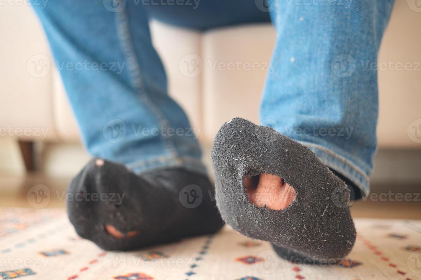 men feet with dirty socks while sitting on sofa photo