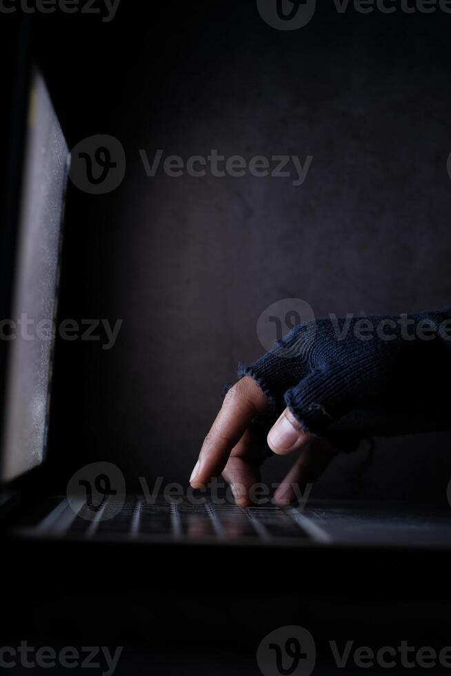Close up of hacker hand stealing data from laptop photo