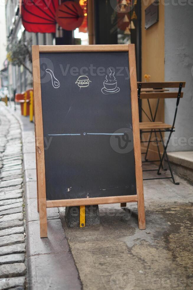 Empty wooden blackboard mockup standing outdoors in front of cafe photo