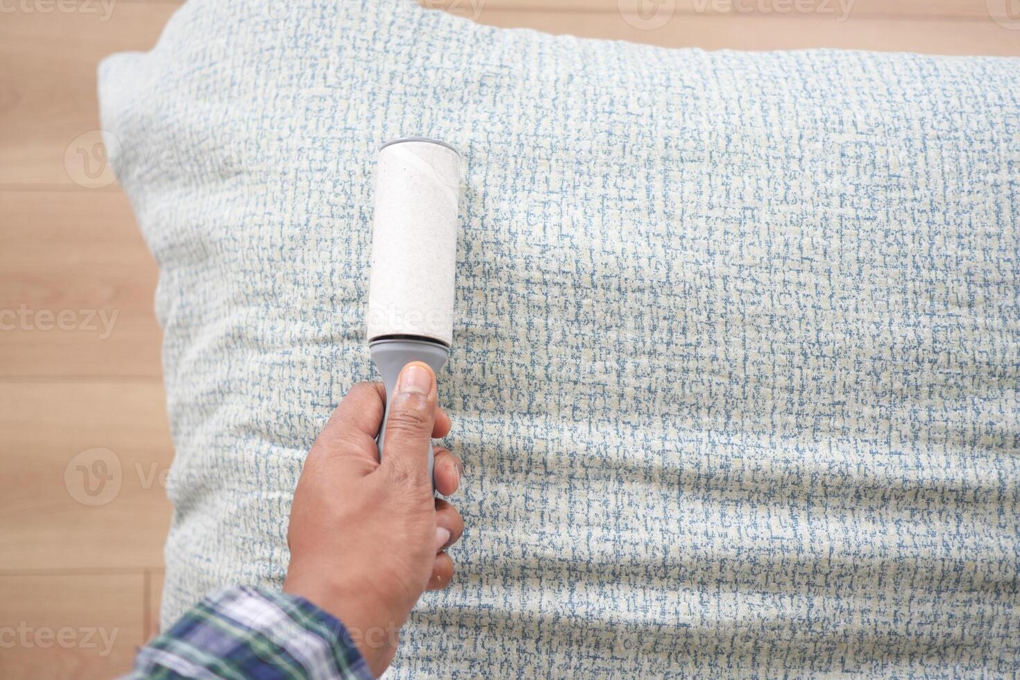 using an adhesive roller to remove lint and fluff from a bed . photo