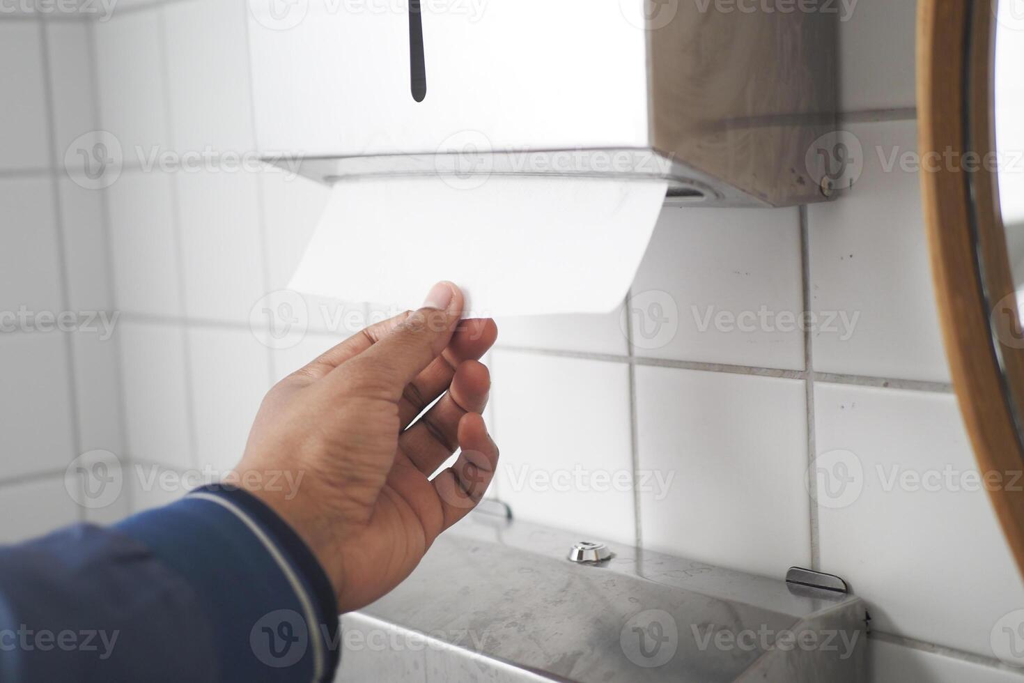 A person is using a paper towel dispenser in a public restroom photo