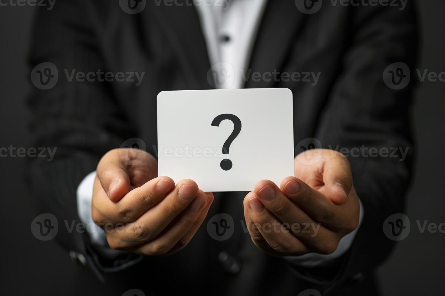 male hands in a black business suit hold a white card with a question mark photo