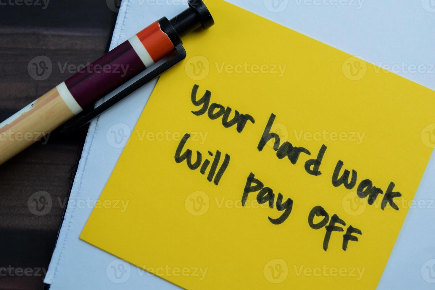Concept of Your Hard Work Will Pay Off write on sticky notes isolated on Wooden Table. photo